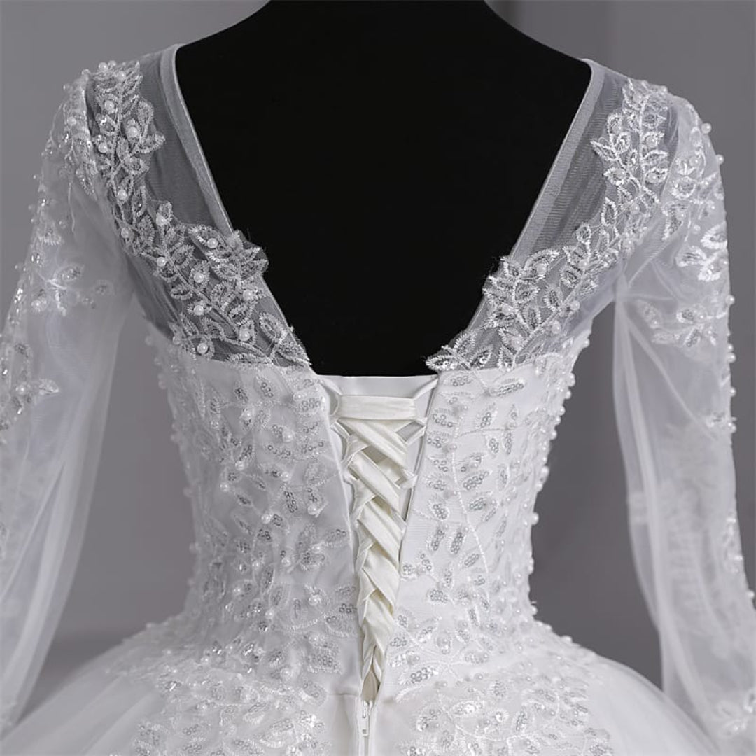 Elegant white layered bridal gown with intricate lace appliqué and a romantic full skirt