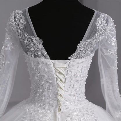 Elegant white layered bridal gown with intricate lace appliqué and a romantic full skirt