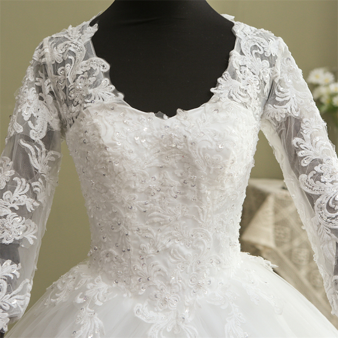 Elegant Christian bridal ball gown with sheer lace sleeves and embroidered hemline by GownLink