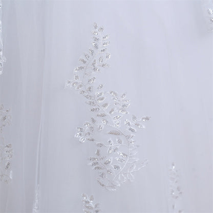 Romantic Christian bridal gown featuring lace embroidery, illusion sleeves, and full tulle skirt