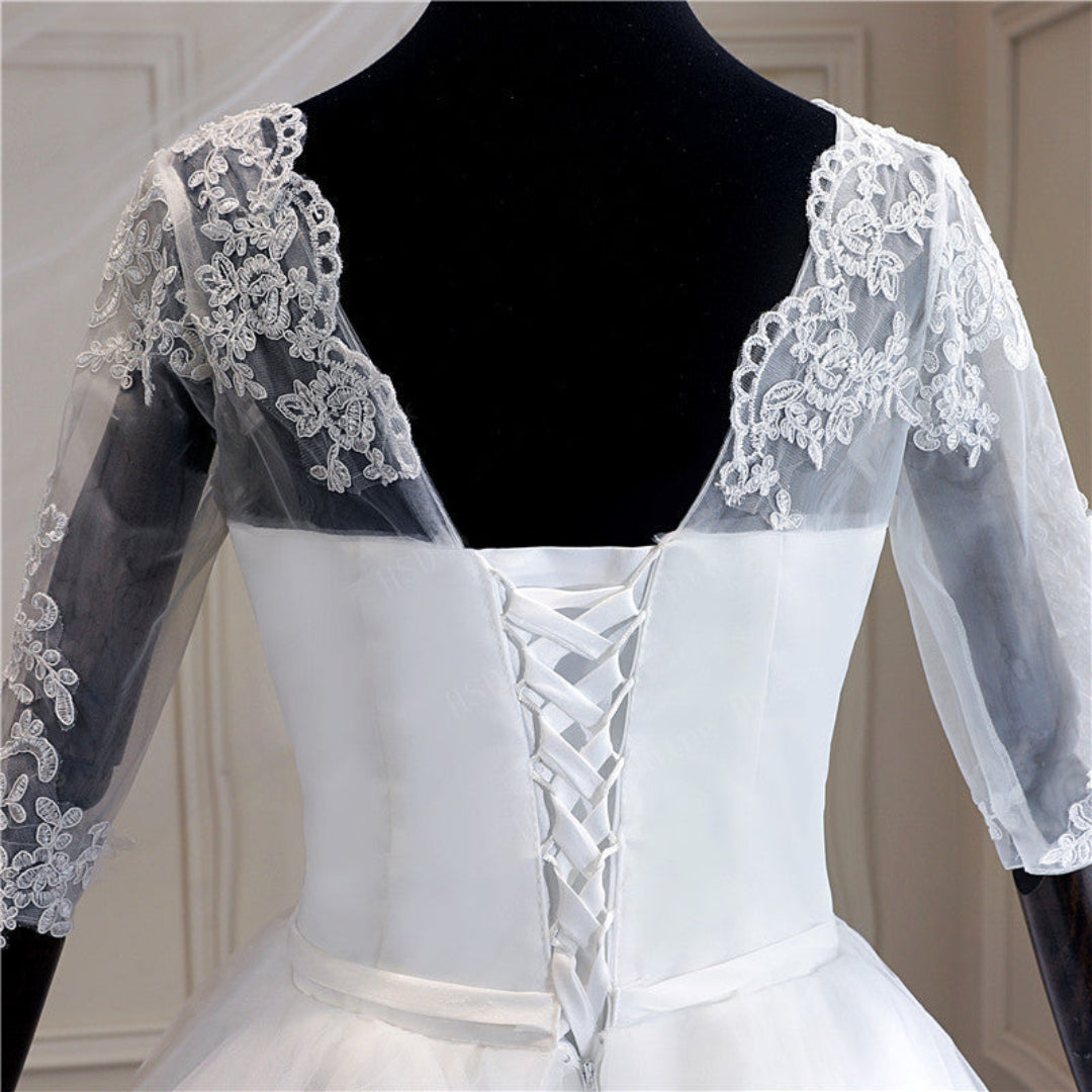 Traditional Christian bridal gown with three-quarter lace sleeves, full ball gown skirt, and elegant cathedral train