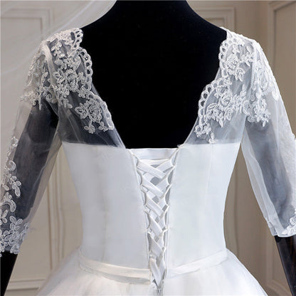 Traditional Christian bridal gown with three-quarter lace sleeves, full ball gown skirt, and elegant cathedral train