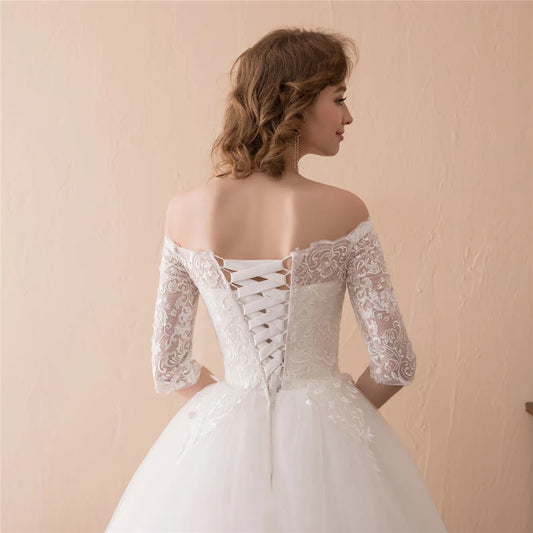 White Christian bridal gown with off-shoulder neckline, lace sleeves, and full princess silhouette
