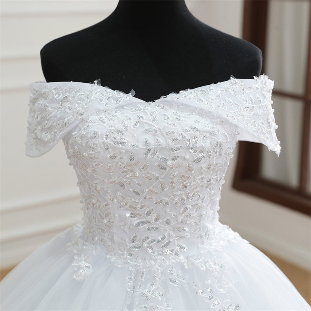 White Christian wedding dress with off-shoulder neckline, lace bodice, and flowing train