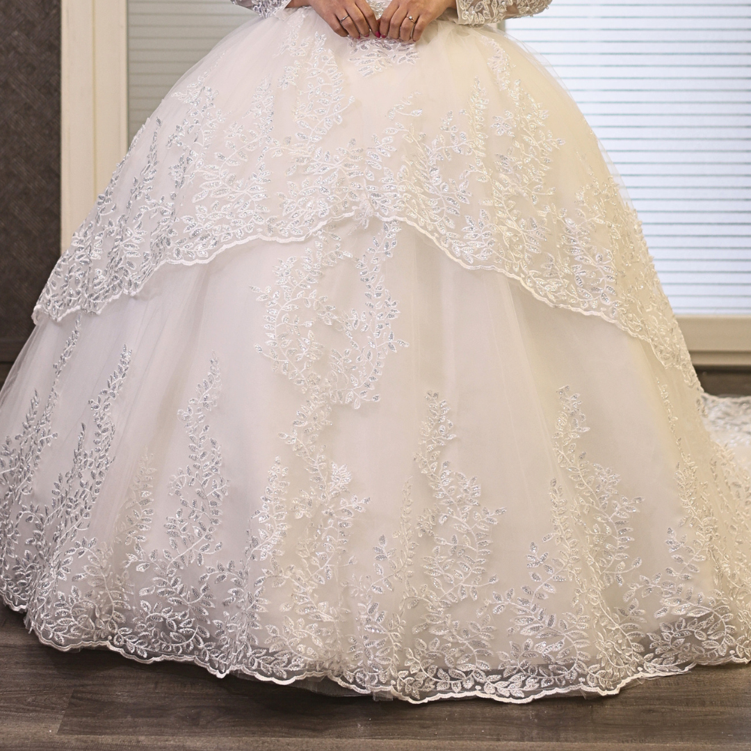 Romantic Christian bridal dress featuring floral lace appliqué, long sleeves, and a full ball gown silhouette